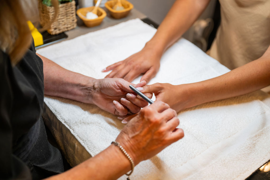 Several people&rsquo;s hands hold a pair of hands together while someone trims nails or grooming at a spa on a towel.
