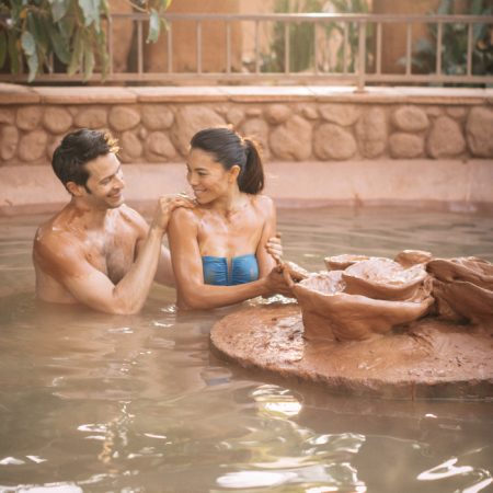 A couple on a day spa retreat in a clay mud bath at Club Mud